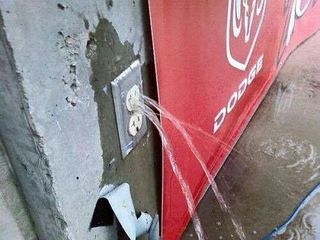 A power socket in a wall with water streaming out
