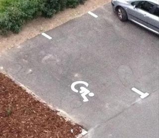 3 steps of an outdoor staircase with a big wheelchair sign painted on it