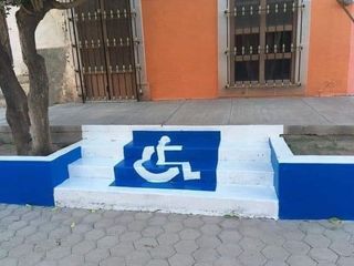 3 steps of an outdoor staircase with a big wheelchair sign painted on it