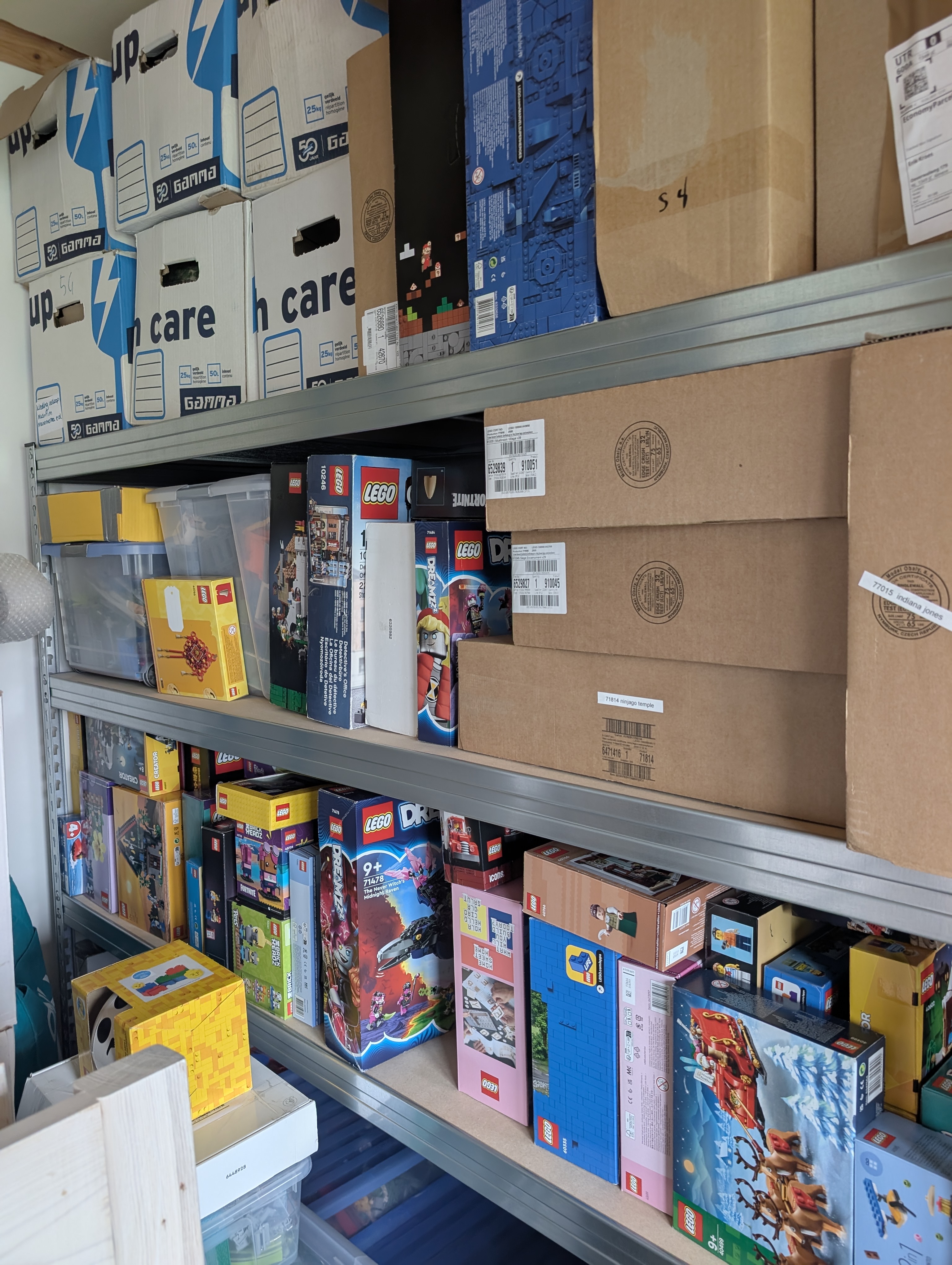 A shelving unit with a wild assortments of moving boxes, lego boxes, shipping boxes and plastic storage boxes