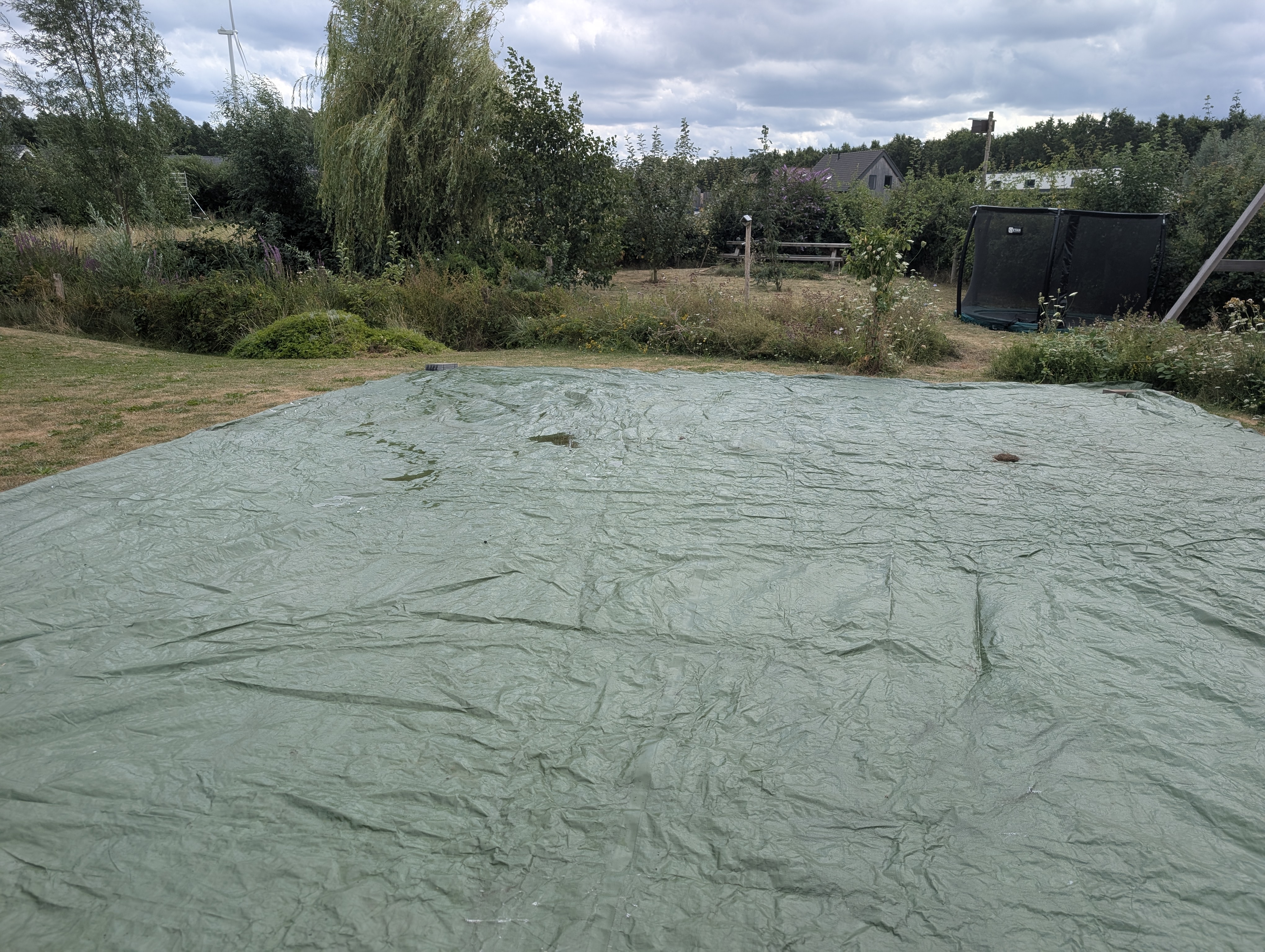 A huge green tarpaulin covering a lawn.